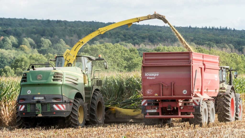 A tractor working through a dense crop field highlights the need for advanced agricultural resilience. Farmers must monitor ECMWF climate models closely to prepare for the heavy rains expected from a Record-Strength El Niño 2026.