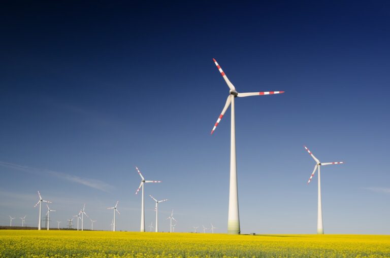 A scenic view of modern windmills spinning against a clear blue sky, symbolizing renewable energy and sustainable practices in action.