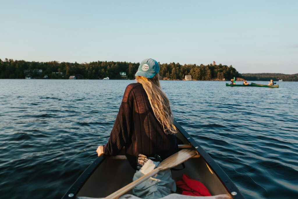 Woman in a brown jacket and white goggles sitting on a boat during daytime while collecting water samples to study microplastics in the Great Lakes
