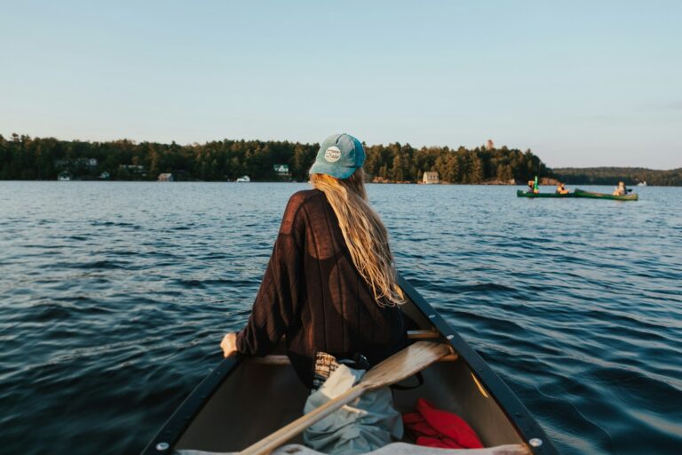 Woman in a brown jacket and white goggles sitting on a boat during daytime while collecting water samples to study microplastics in the Great Lakes