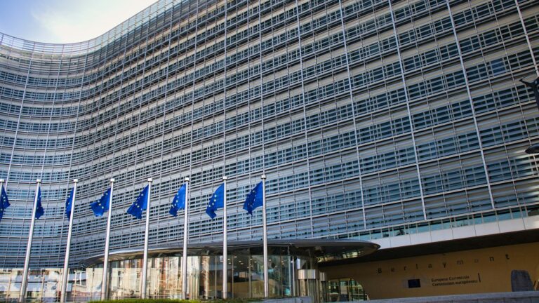 European Commission Berlaymont building in Brussels with EU flags, where the CSRD and ESRS rules are set