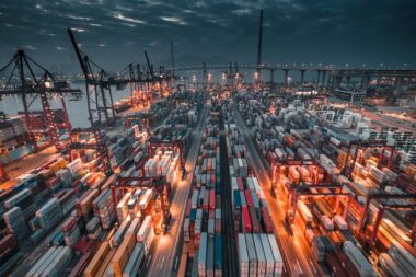 Busy container port terminal at dusk, where steel, aluminium and other CBAM goods enter the EU
