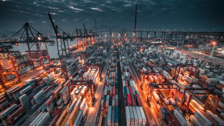 Busy container port terminal at dusk, where steel, aluminium and other CBAM goods enter the EU