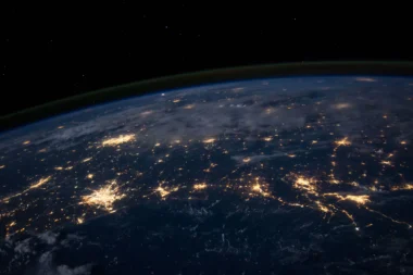 Earth at night seen from orbit, with city lights across continents