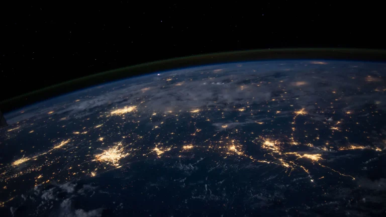 Earth at night seen from orbit, with city lights across continents