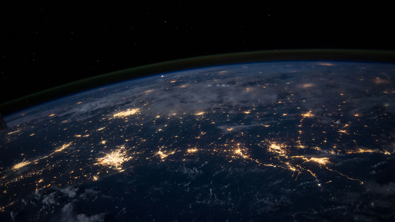 Earth at night seen from orbit, with city lights across continents