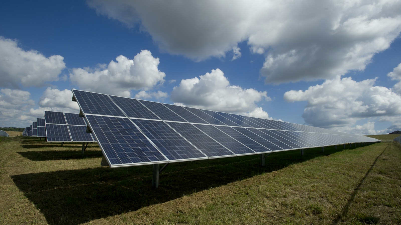 Solar panels under a blue sky with clouds