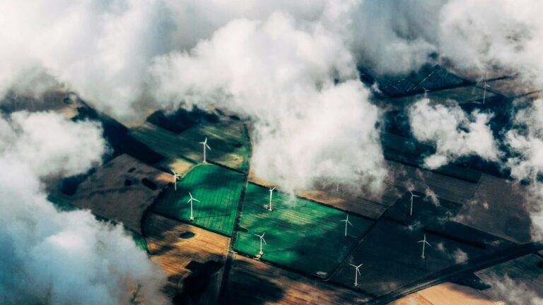 Aerial view of a wind turbine array across farmland, illustrating corporate net-zero decarbonization pathways